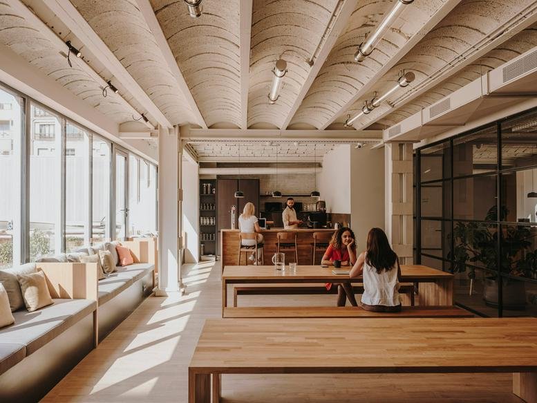 Spacious communal lounge at Calle Gran Via de les Corts Catalanes, 613, Barcelona with vaulted ceilings and wooden tables.