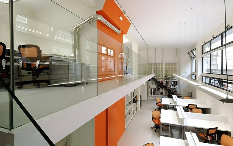 Modern open-plan office at Calle Pascual Hermanos 3 with orange feature walls and mezzanine workspace.