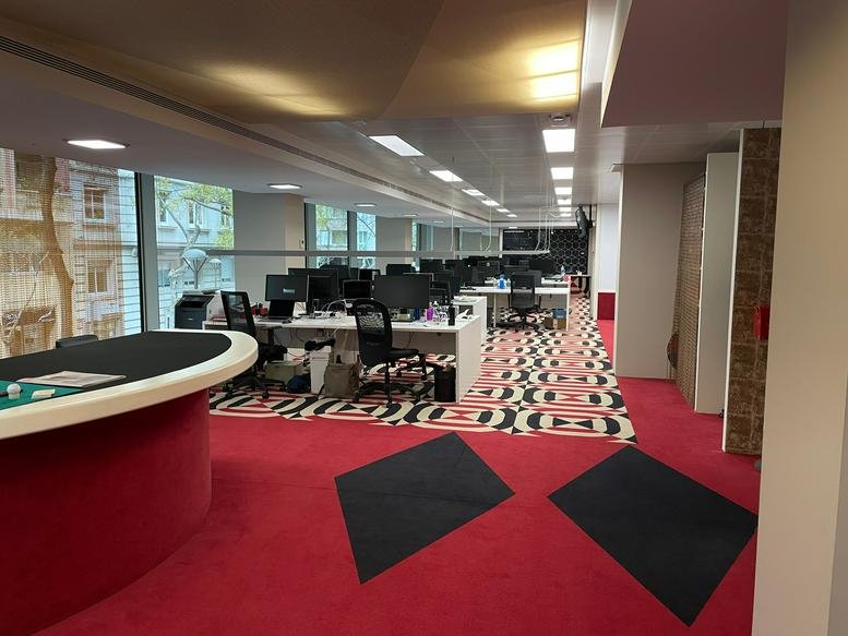 Open interior of TGA Travessera de Gràcia Amigó showing diverse work zones and a game table.