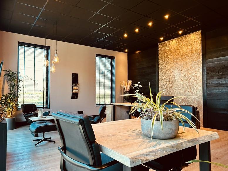 Spacious main office area at Deltazijde 20B with natural wood desks, black ceilings, and vibrant indoor plants.