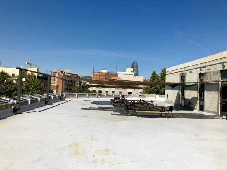 Spacious rooftop terrace with picnic tables at District 22, Carrer de Pujades, 112, Barcelona.