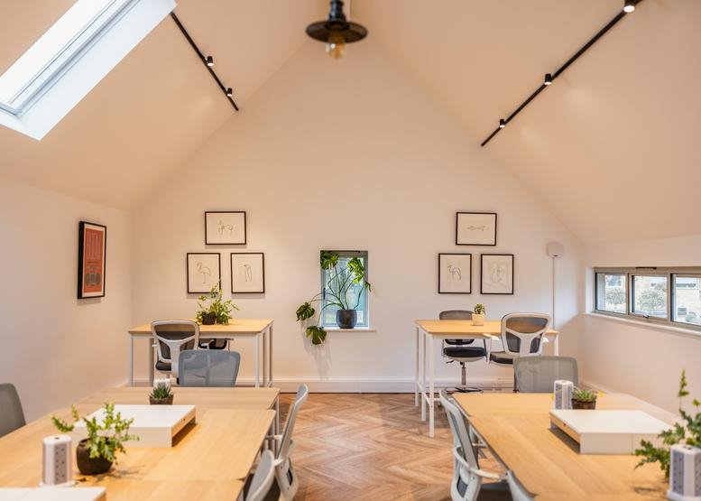 Symmetrical view of a bright attic office with vaulted ceilings, skylights, and multiple desk pods.