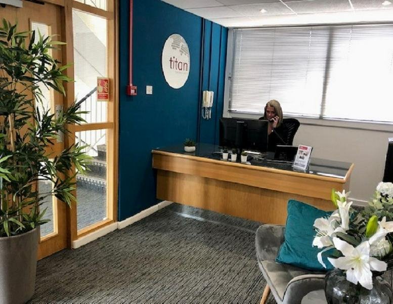 Reception area at Euroway House with a branded teal feature wall and wooden front desk.