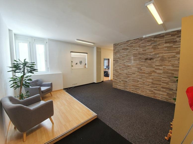 Spacious reception area with armchairs and a stone feature wall at Galerie Saint-François B, Lausanne.