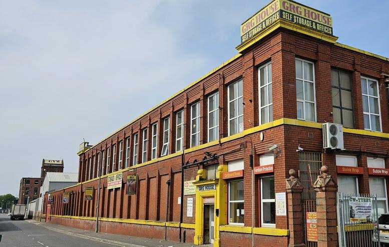 Exterior view of the red brick industrial-style GRG House with yellow accents.