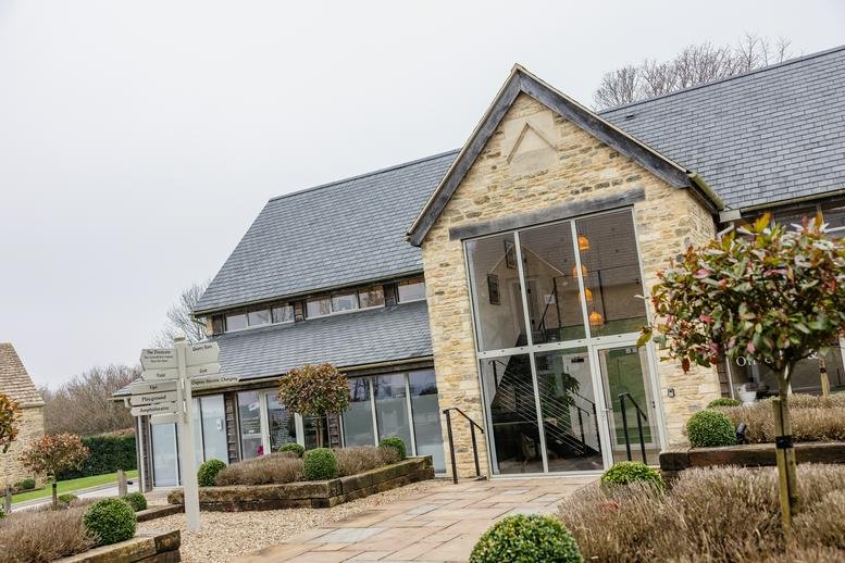 Front entrance of the converted barn building with large glass doors and contemporary landscaping.