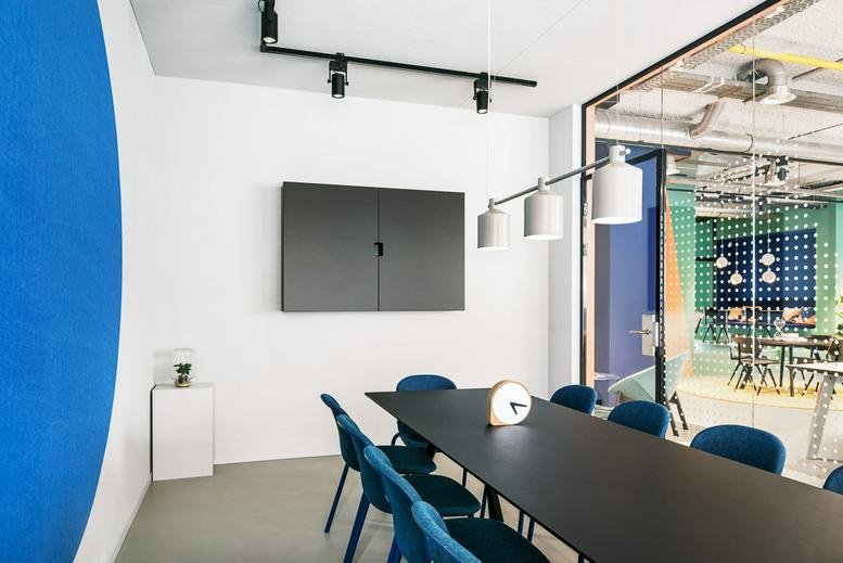 Meeting room at Hoefkade 9, The Hague, South Holland with a black table and blue chairs against a blue feature wall.