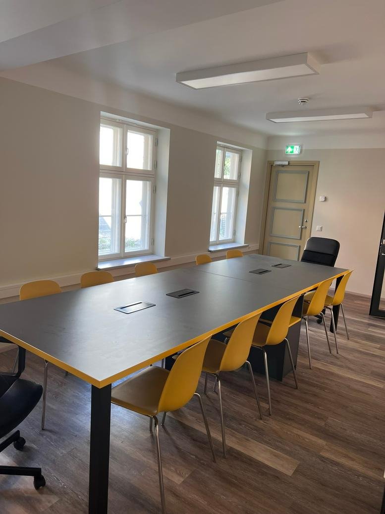 Spacious meeting room at Hommiku 5, Pärnu, Estonia with a large dark table and yellow chairs.