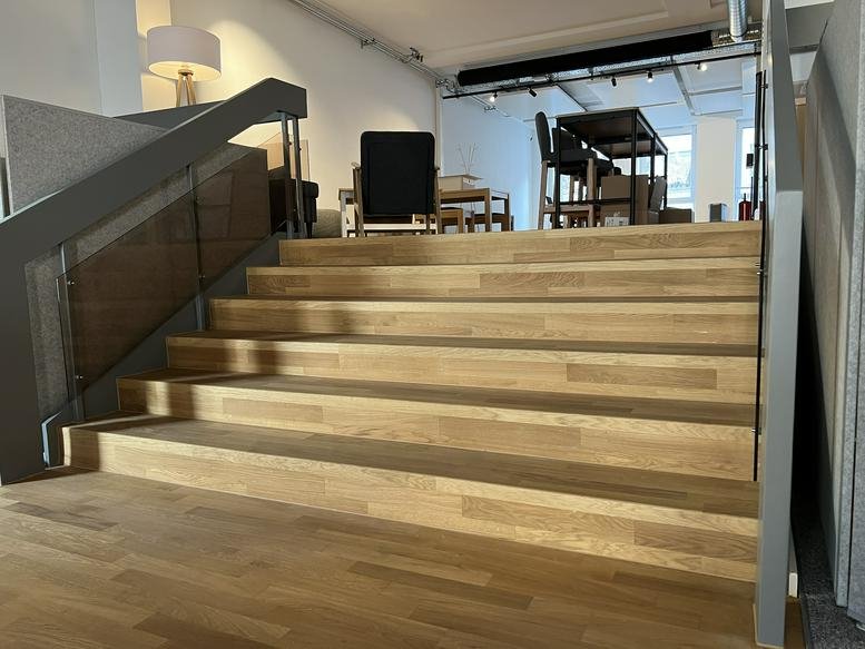 Wide wooden staircase leading to an upper-level breakout area with furniture.
