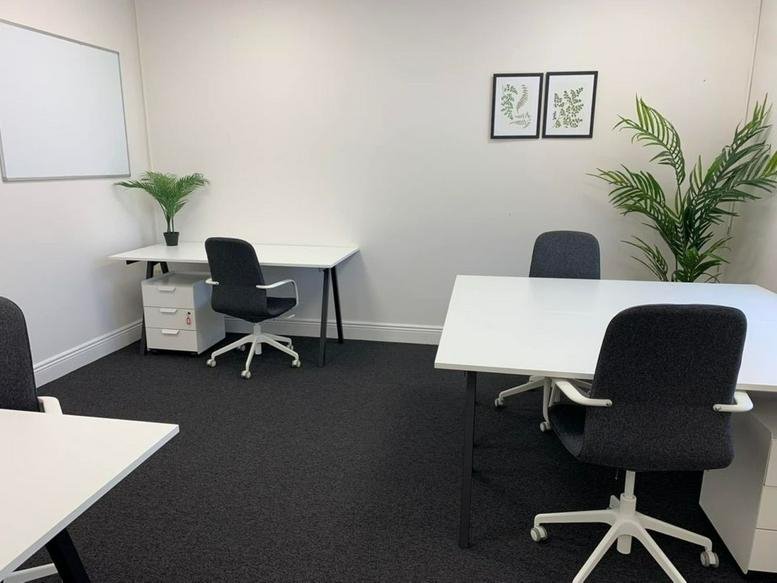 Spacious three-desk office suite with white tables and green plants at Unit 1, Knockmitten Business Park.