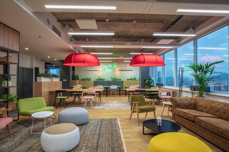 Spacious communal lounge at myhive Vajnorska 100/A featuring colorful furniture and bright red pendant lights.