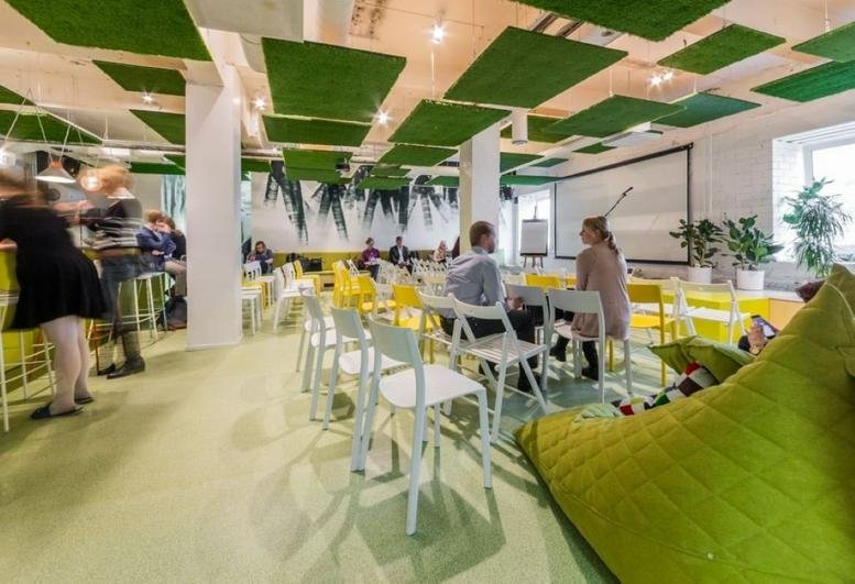 Spacious coworking lounge at Pärnu Maantee 148 with artificial turf ceiling panels and bean bag seating.