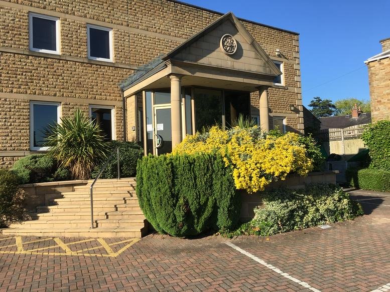 Exterior view of the stone facade and portico entrance at Park House, 920 Bradford Road.