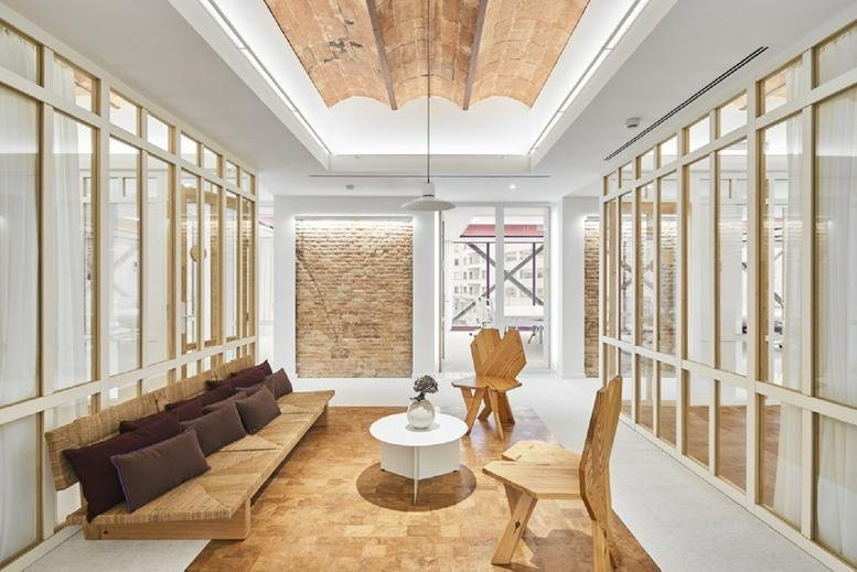 Spacious reception at Plaza de Catalunya, 9, Barcelona with wood ceilings and warm lighting.