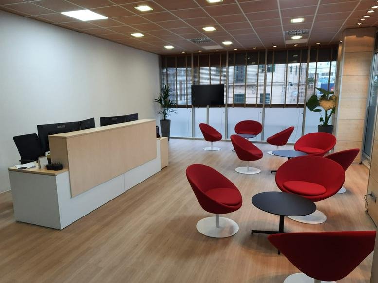 Spacious reception area with a modern desk and bright red lounge seating at Plaza Mirador Remigia Caubet 5.