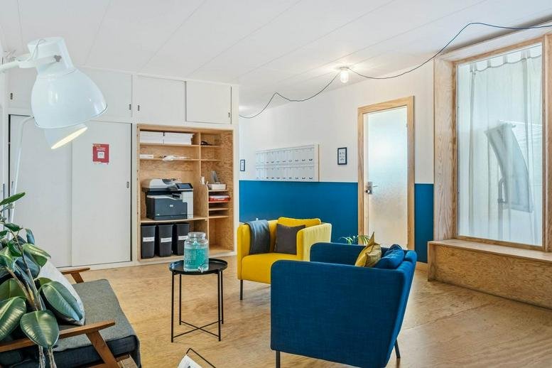Colorful lounge area at Route des jeunes 105A featuring blue and yellow armchairs and a plant.