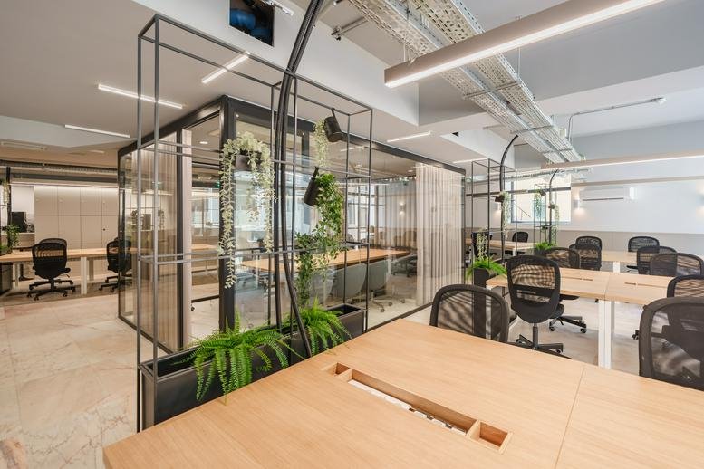 Spacious open-plan workspace at Rua da Firmeza 369 with glass partitions and indoor plants.
