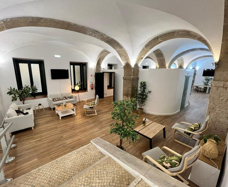Spacious communal lounge at Rua Da Madalena 111 with vaulted ceilings, stone arches, and modern furniture.