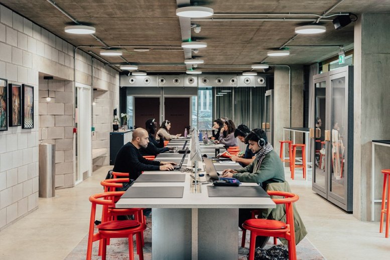 Spacious open-plan coworking area at Design District, 13 Soames Walk with long tables and red stools.