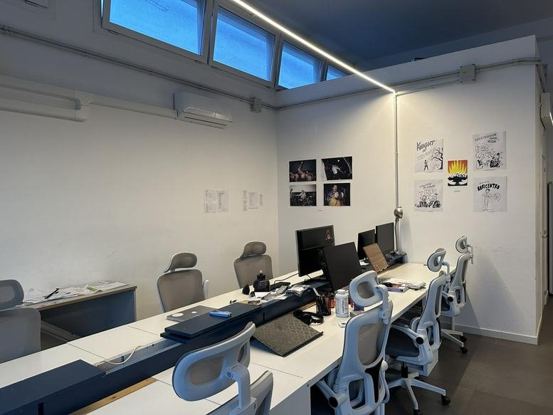 Spacious open-plan IfInApulia Workspace with modern ergonomic chairs, white desks, and natural light from clerestory windows.