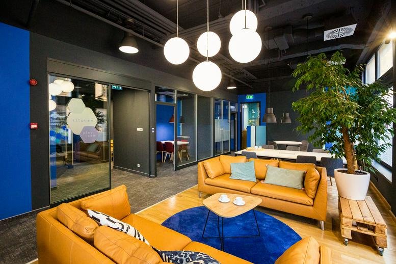 Lounge area with tan leather sofas, a blue circular rug, and globe pendant lights.