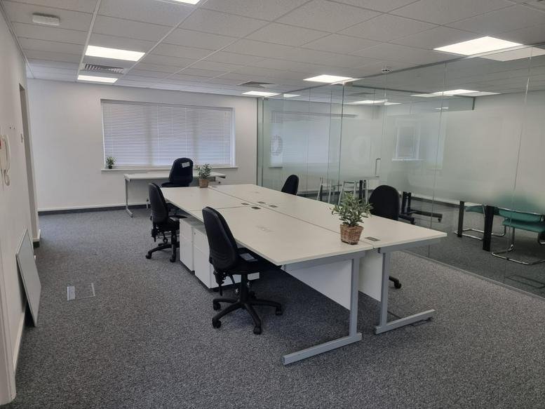Bright open-plan office suite at 2 Forest Court featuring large white desks and glass partitions.