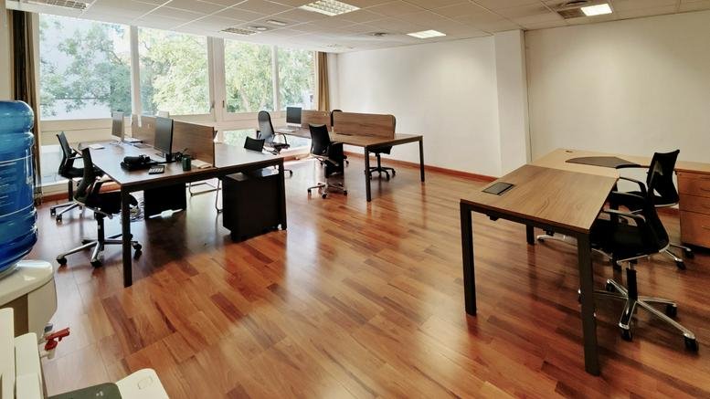 Large open-plan workspace at 22 Carrer Numància with multiple wooden desks and ergonomic chairs.