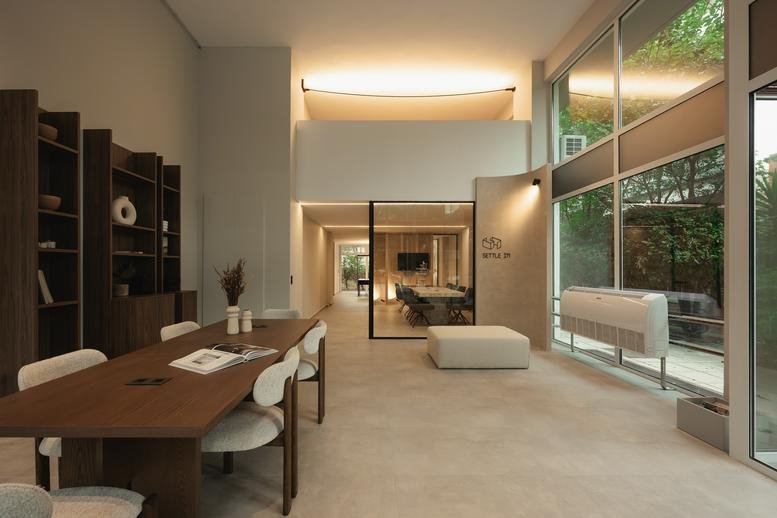 Spacious communal lounge at Settle In, 3 Καθηγητού Ρωσσίδου with wooden dining table and large windows.