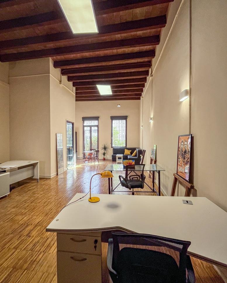 Spacious open-plan workspace at Casa Sidral, 36 Carrer de Sant Eusebi with high beamed ceilings and wood floors.