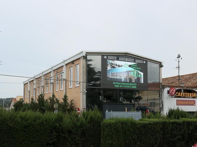 Exterior of 44 Carrer Estrella, Sant Quirze del Vallès, featuring a large digital display on the brick facade.