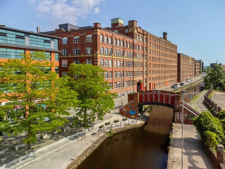 Exterior view of the historic red brick factory conversion at 51-53 Ducie Street beside a canal.