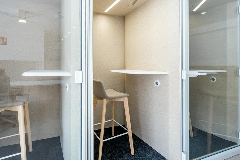Private soundproof phone booths with high stools for focused work.