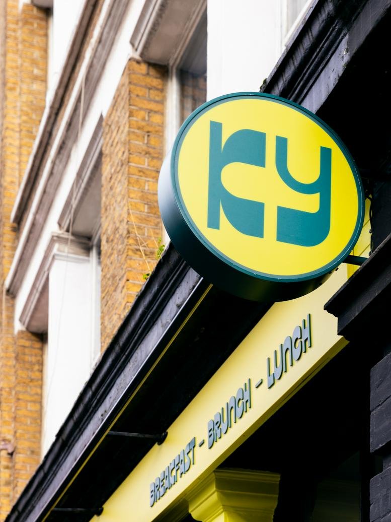 Circular yellow building sign featuring the KY logo against a brick facade.