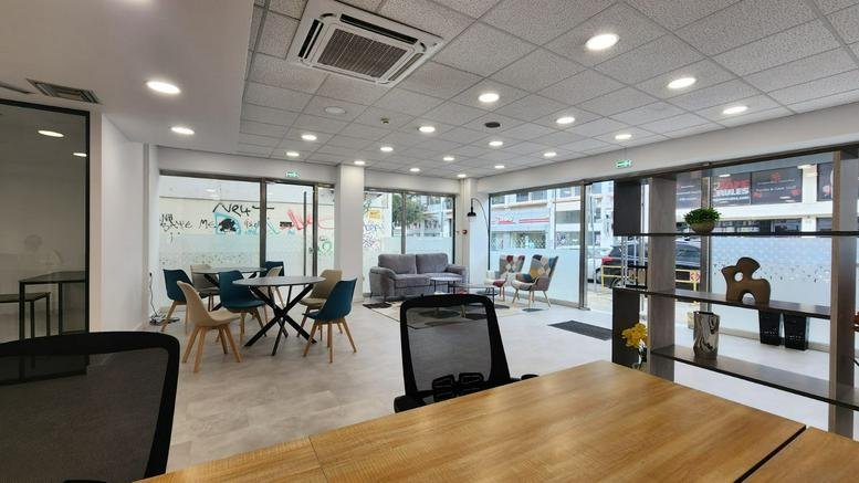 Bright communal lounge area with colourful blue chairs, a grey sofa, and wooden tables.