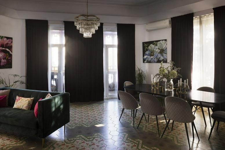 Wide view of a combined lounge and dining area featuring patterned tile floors and a crystal chandelier.