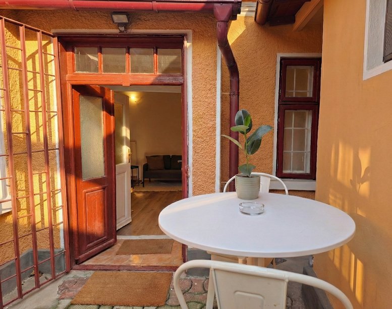 The entrance to 88 Strada Măgura Vulturului featuring a white bistro table and potted plant.