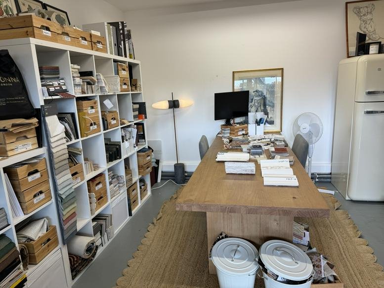 Bright creative studio with wood drafting table and extensive white shelving units.