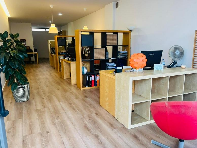 Reception area with a light wood desk, orange light fixture, and indoor plant.