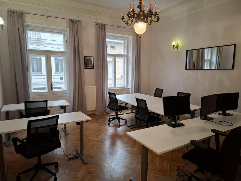 Spacious open-plan workspace at Trading Hub, Szív utca 3-5, featuring white desks and a crystal chandelier.