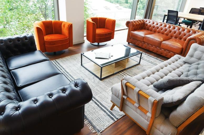 Spacious lounge at Strada Nicolae Iorga 5 with tufted leather sofas and vibrant orange armchairs.