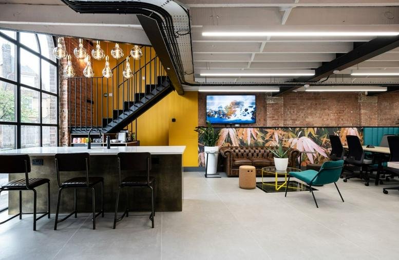 Spacious communal lounge at The Old Pumphouse, 1A Stonecross, St Albans, featuring a bar and feature staircase.