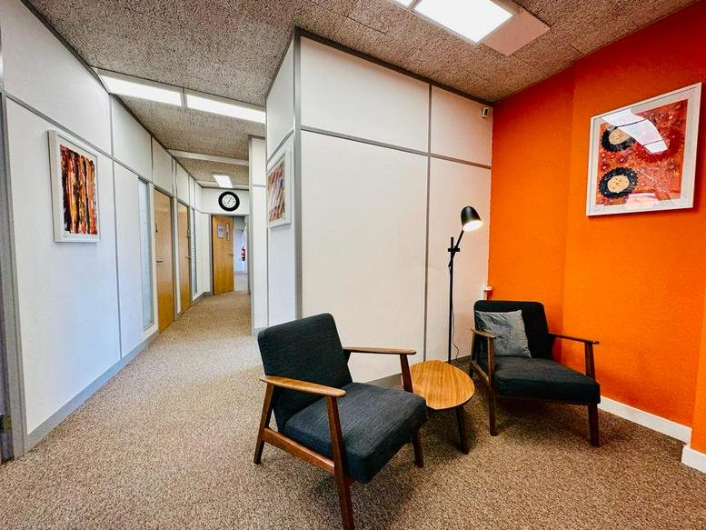 Reception lounge at The Workay Maidenhead with a bold orange feature wall and stylish armchairs.