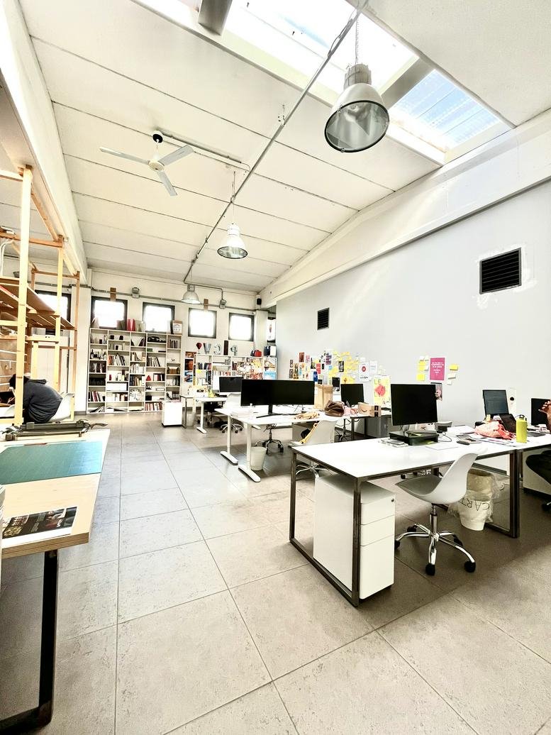 Spacious, sunlit open-plan office at Via Strecciola 5, Malgrate with high ceilings and skylights.