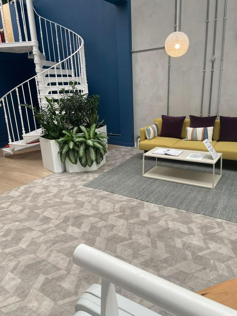 Bright reception area at Vidya, Unit 4, Holford Yard with a yellow sofa, spiral staircase, and lush green plants.