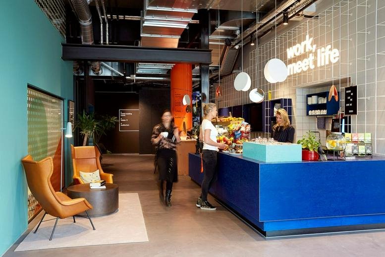 A vibrant blue reception desk with a white neon sign saying work meet life at Wibautstraat 131D, Amsterdam.