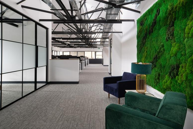 Spacious communal lounge at Winslade House, Winslade Park featuring a vibrant green moss wall and velvet armchairs.