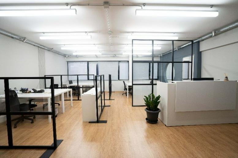 Spacious open-plan workspace featuring glass partitions and a reception desk area.