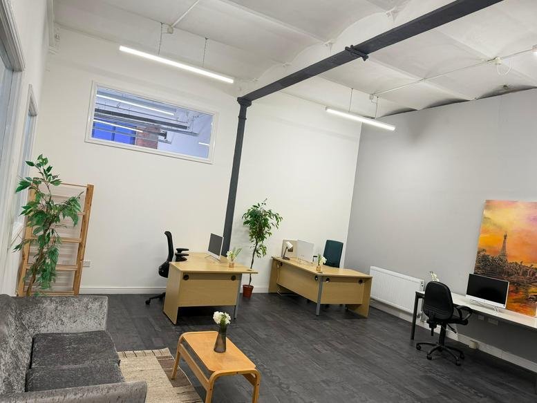 Spacious open-plan office at Crown Street with wooden desks, indoor plants, and natural light.