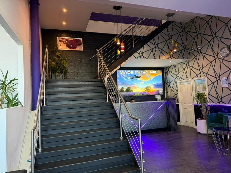 Modern reception lobby at Crown Street featuring a grand staircase and vibrant purple lighting.