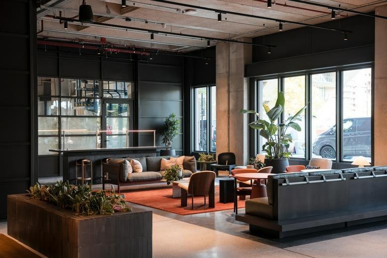 Spacious communal lounge at Deal Porters Way with modern seating, warm rugs, and industrial ceilings.